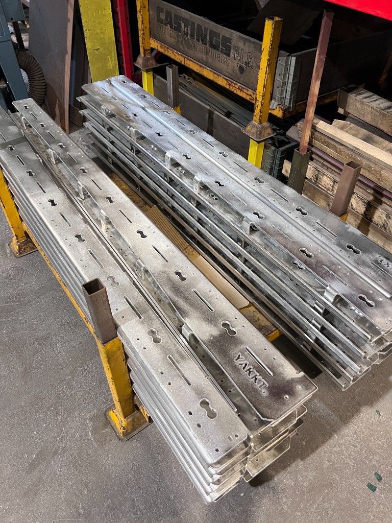 A batch of YAKKT roof rack side rails stacked, ready for powder coating